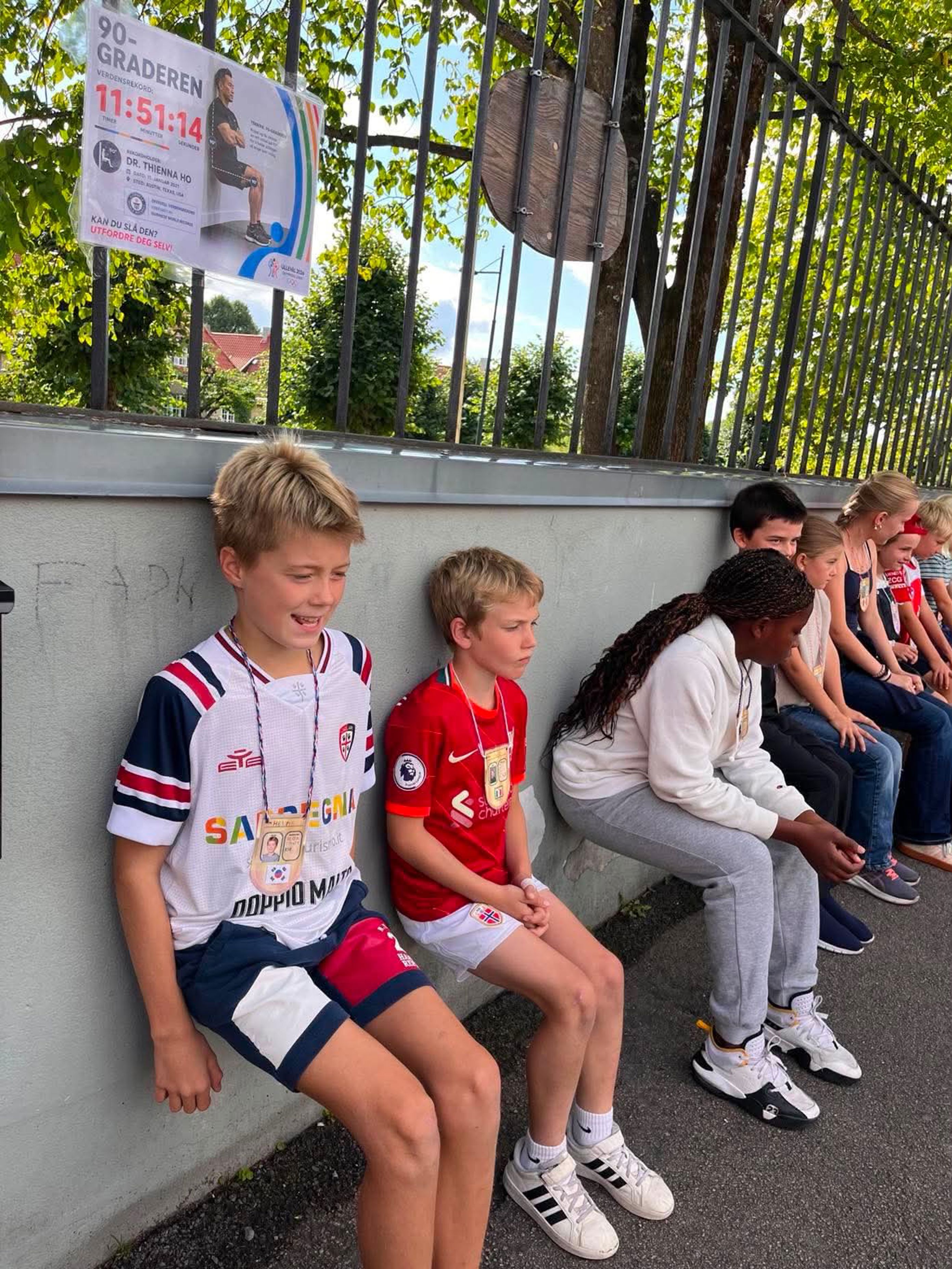 en gruppe barner som sitter på en betongavsats en gruppe barner som sitter på en betongavsats